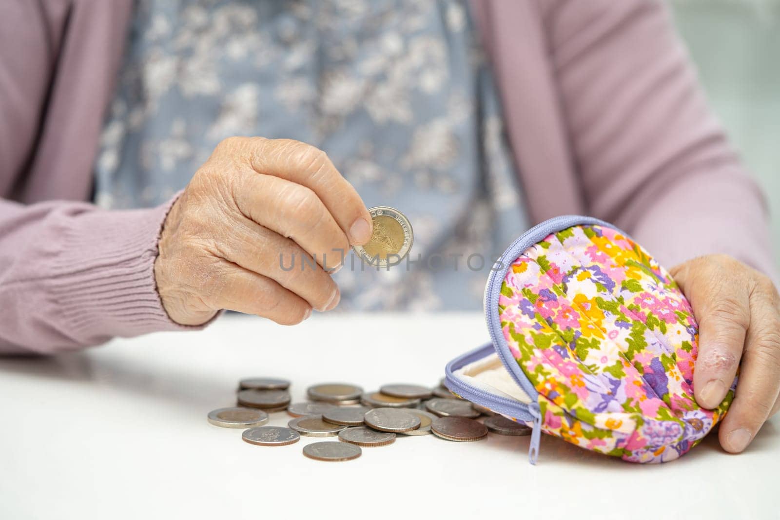 Asian senior woman holding counting coin money in purse. Poverty, saving problem in retirement. by pamai