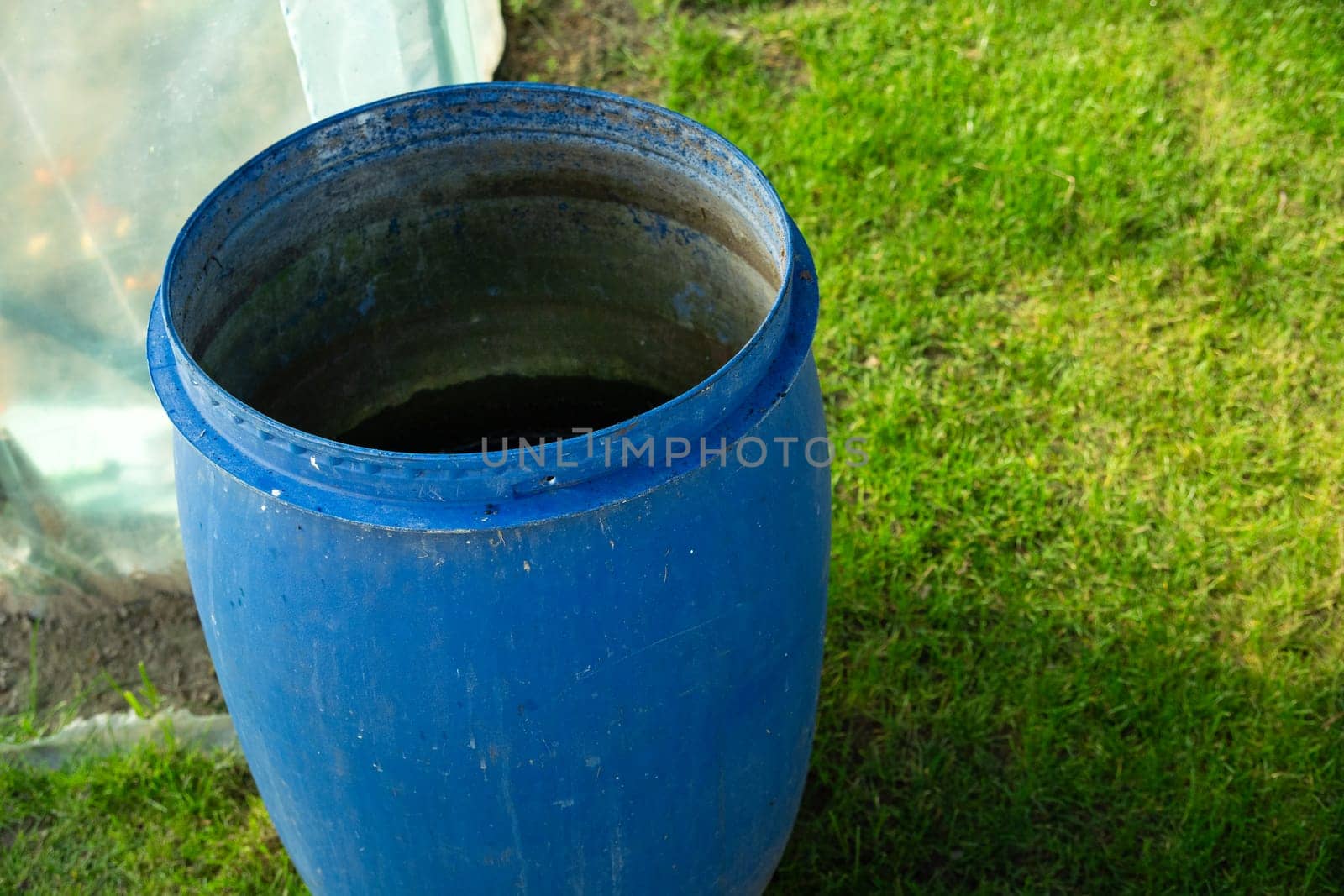 A large blue plastic barrel standing on the green grass