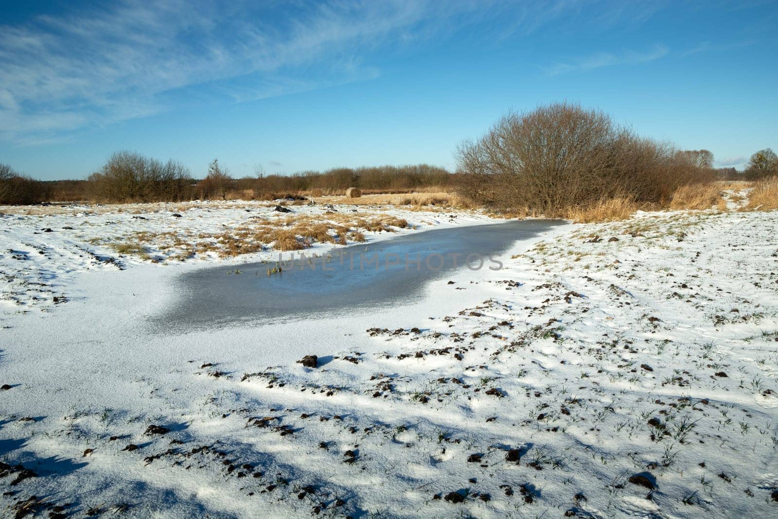 Winter landscape with a view of frozen water and snow on a plowed field, Nowiny, Eastern Poland