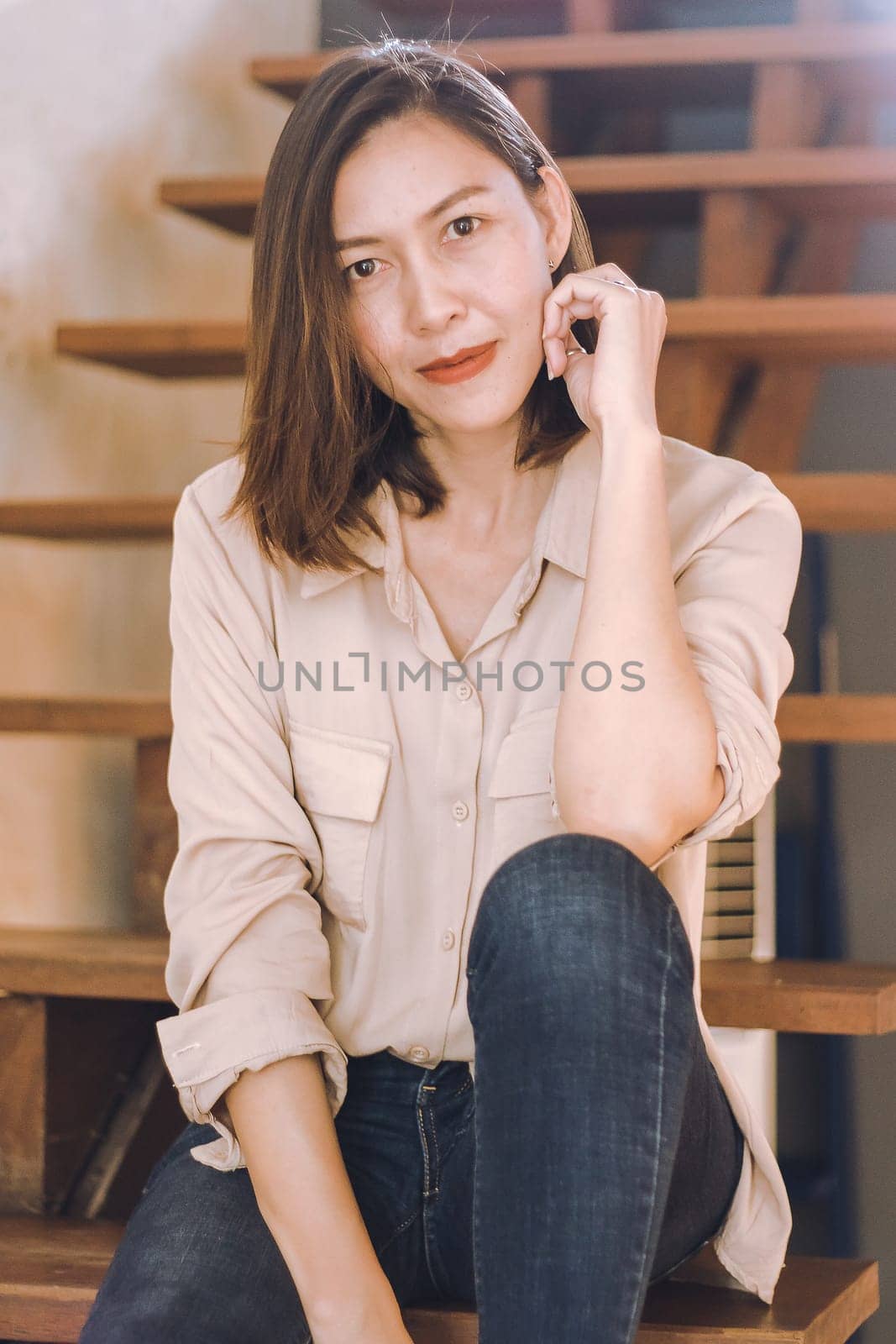 A woman sitting at an old wooden staircase