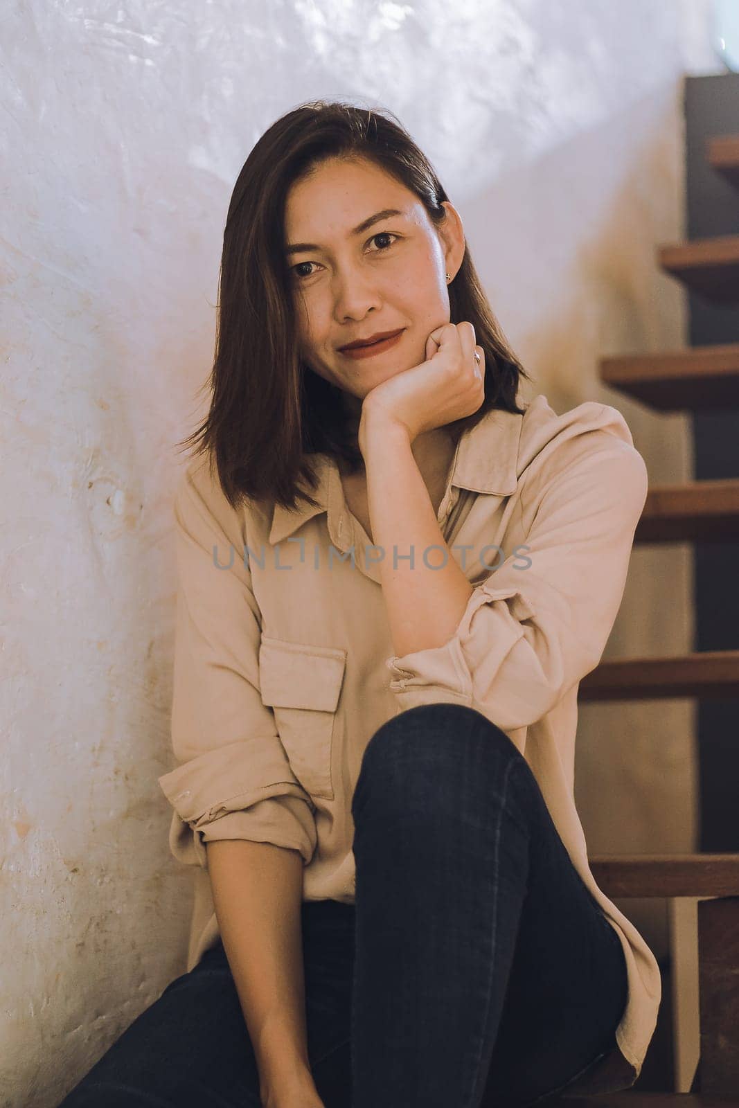 A woman sitting at an old wooden staircase