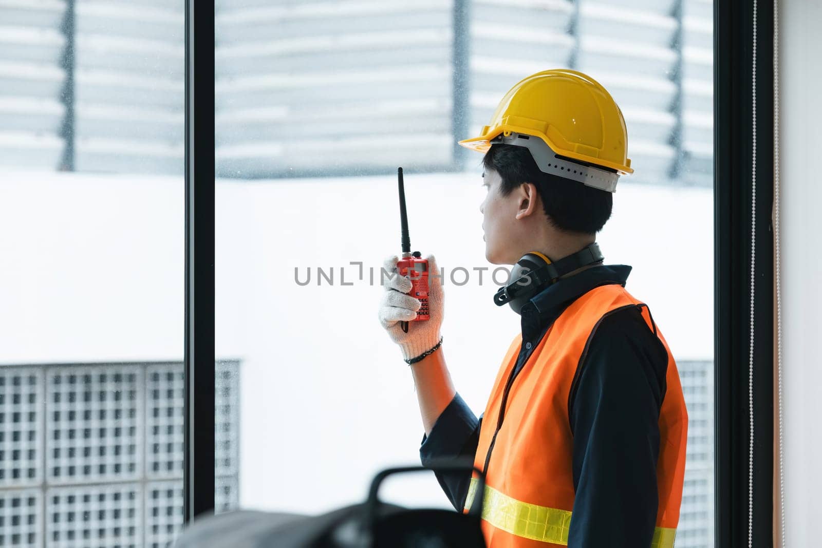 Young Asian engineer talking radio walkie talkie to operate and control the worker employee to build construction..