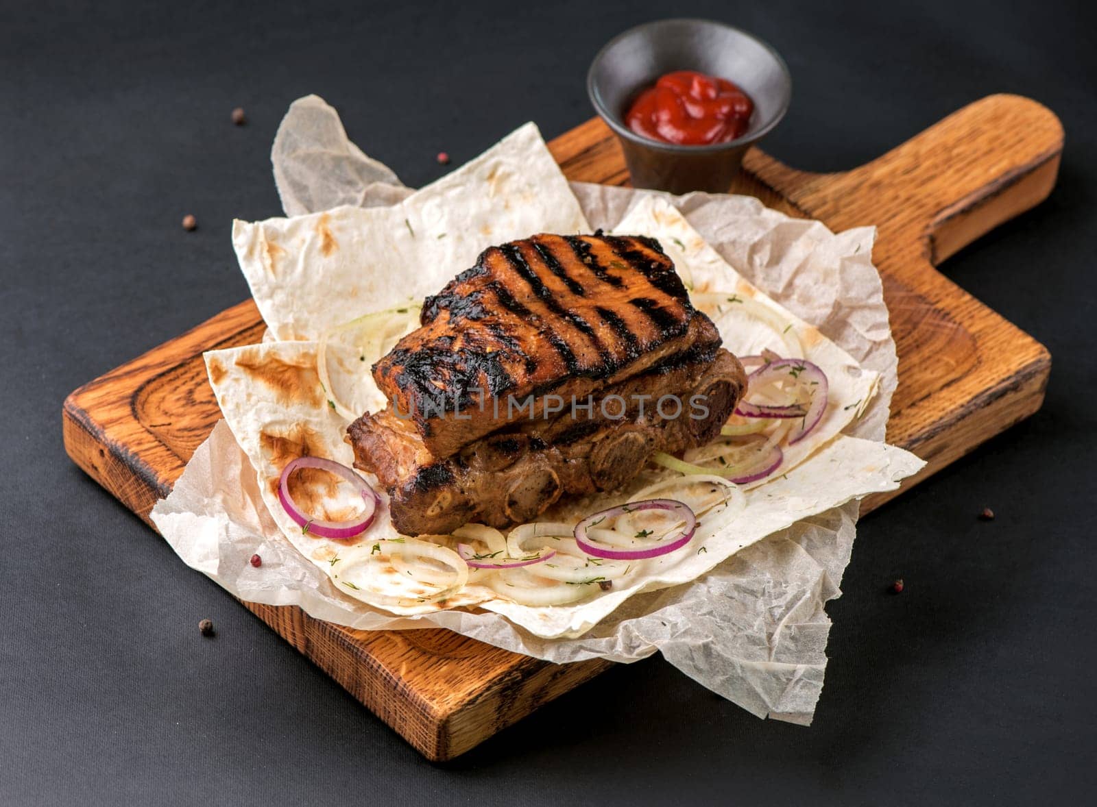 spicy grilled spare ribs on plate over dark stone background with copy space. Top view, flat lay