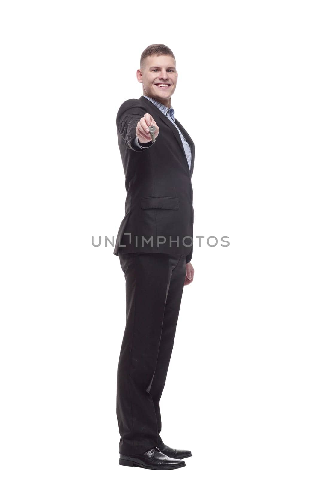 in full growth. happy young businessman with keys in hand . isolated on a white background.