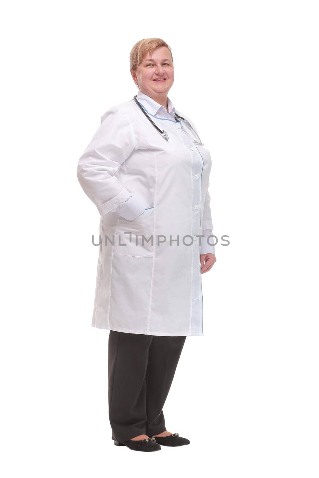 Side view of smiling female doctor with hands in her pockets against a white background
