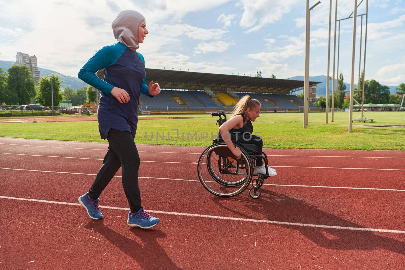 A Muslim woman in a burqa running together with a woman in a wheelchair on the marathon course, preparing for future competitions