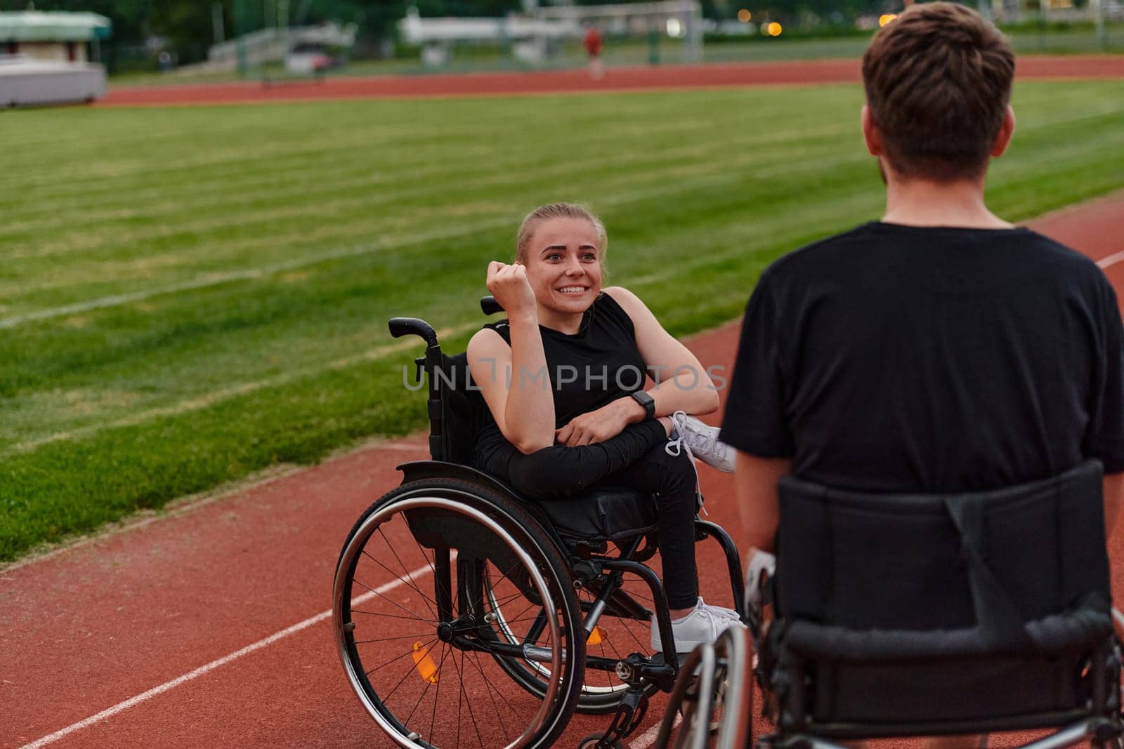 A woman with disability in a wheelchair talking with friend after training on the marathon course.