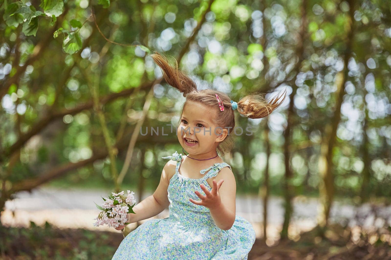charming child in sundress with a bouquet of flowers in the garden.