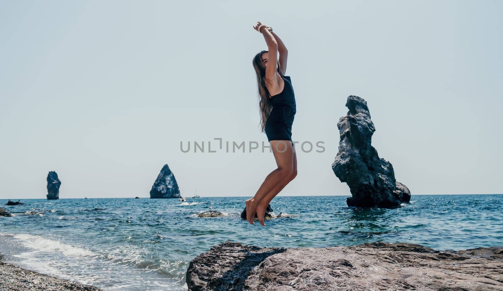 Woman summer travel sea. Happy tourist in hat enjoy taking picture outdoors for memories. Woman traveler posing on the beach at sea surrounded by volcanic mountains, sharing travel adventure journey by panophotograph