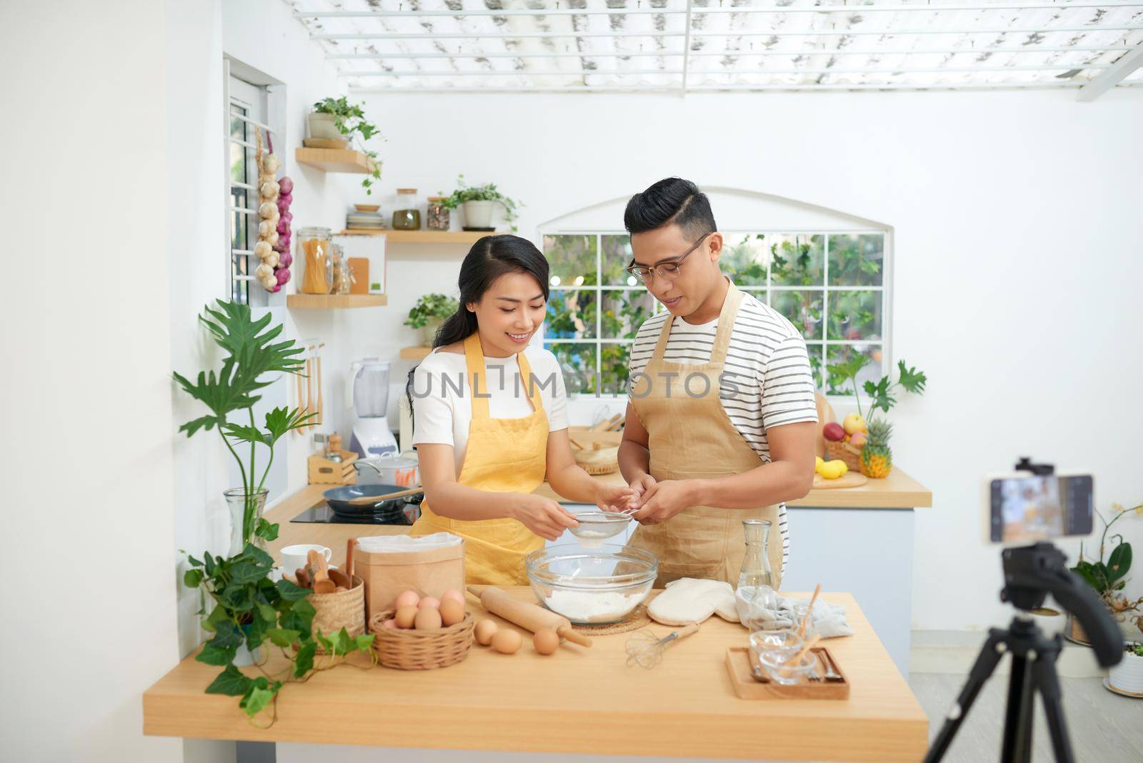 Young asian couple cooking together and recording live video for vlog and social media with professional camera