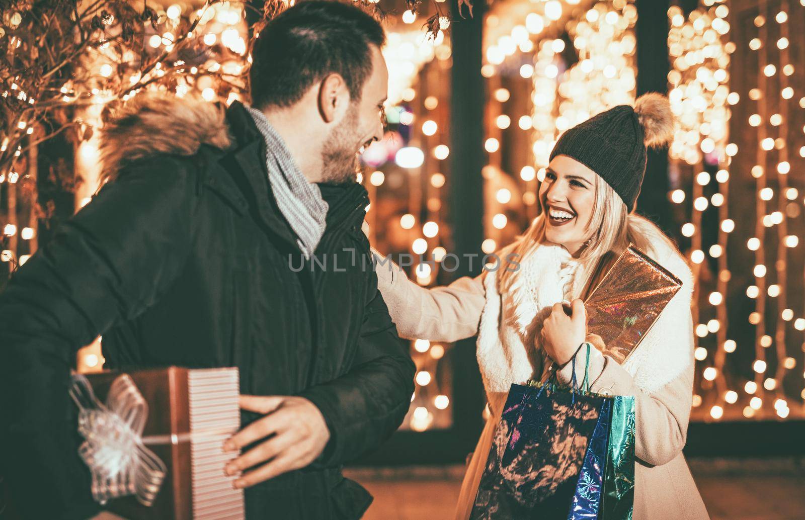 Young beautiful couple meet on the street, stroll through town and having fun buying Christmas gifts in the city mall. 