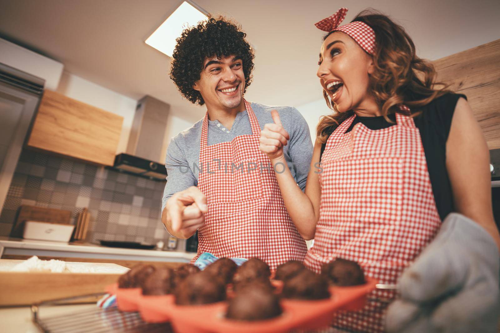 Young couple is very happy with baking muffins witch they are making in their kitchen