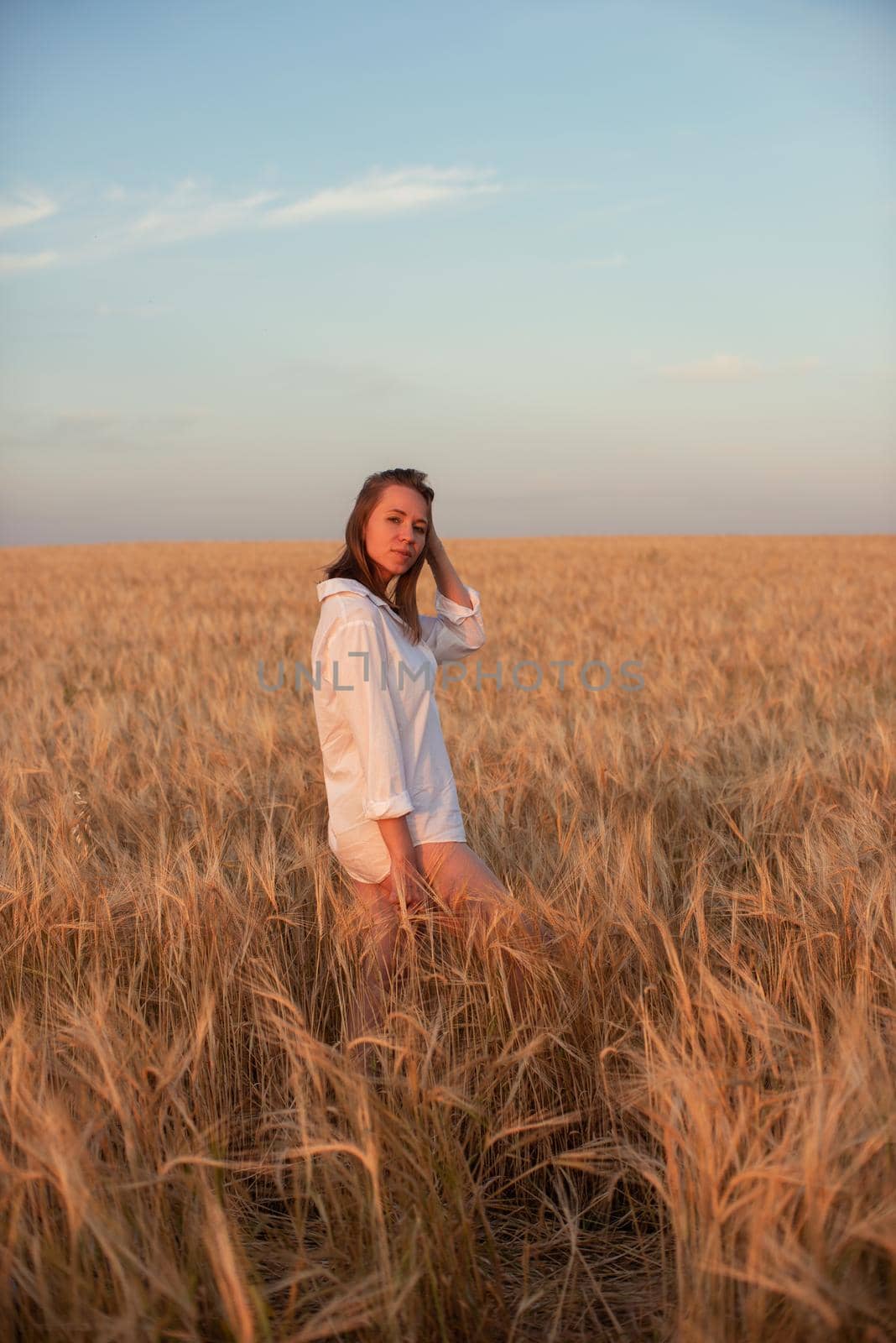Woman in the yellow field of wheat, beauty summer sunset