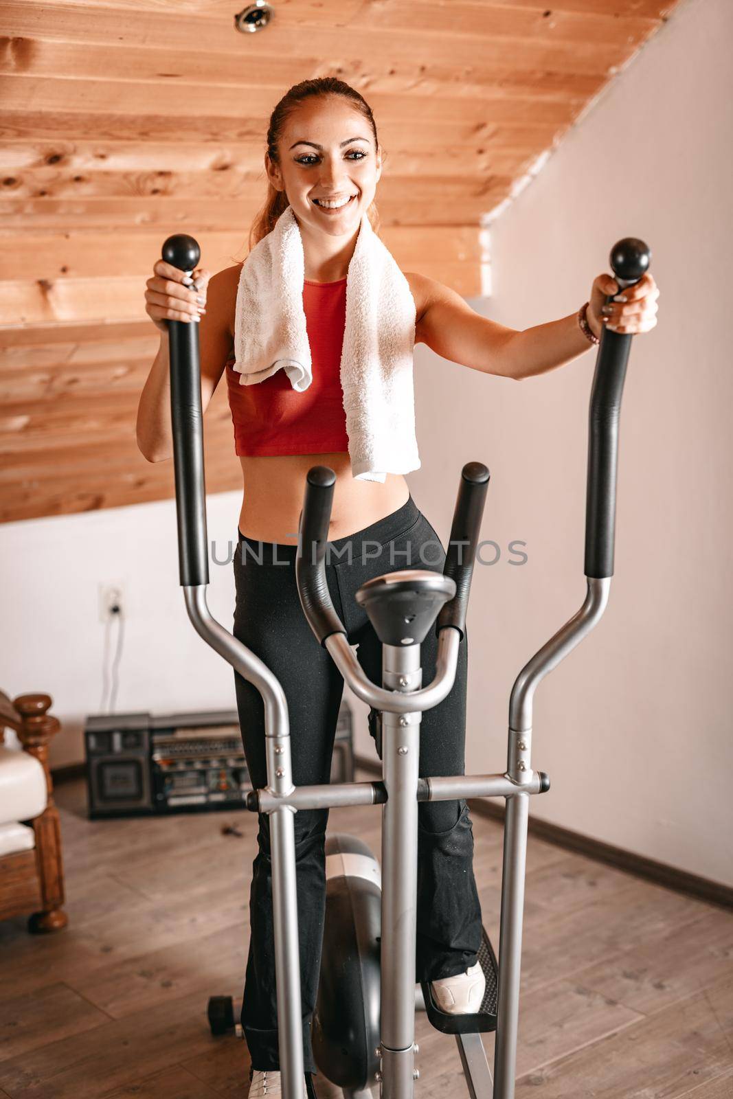 Beautiful young woman exercising on stepper at her home.