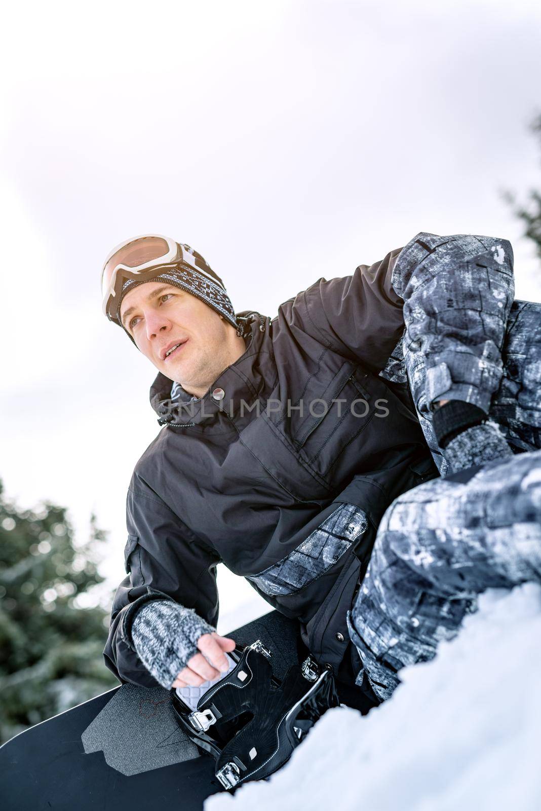 Beautiful young smiling man with snowboard enjoying a winter day. 