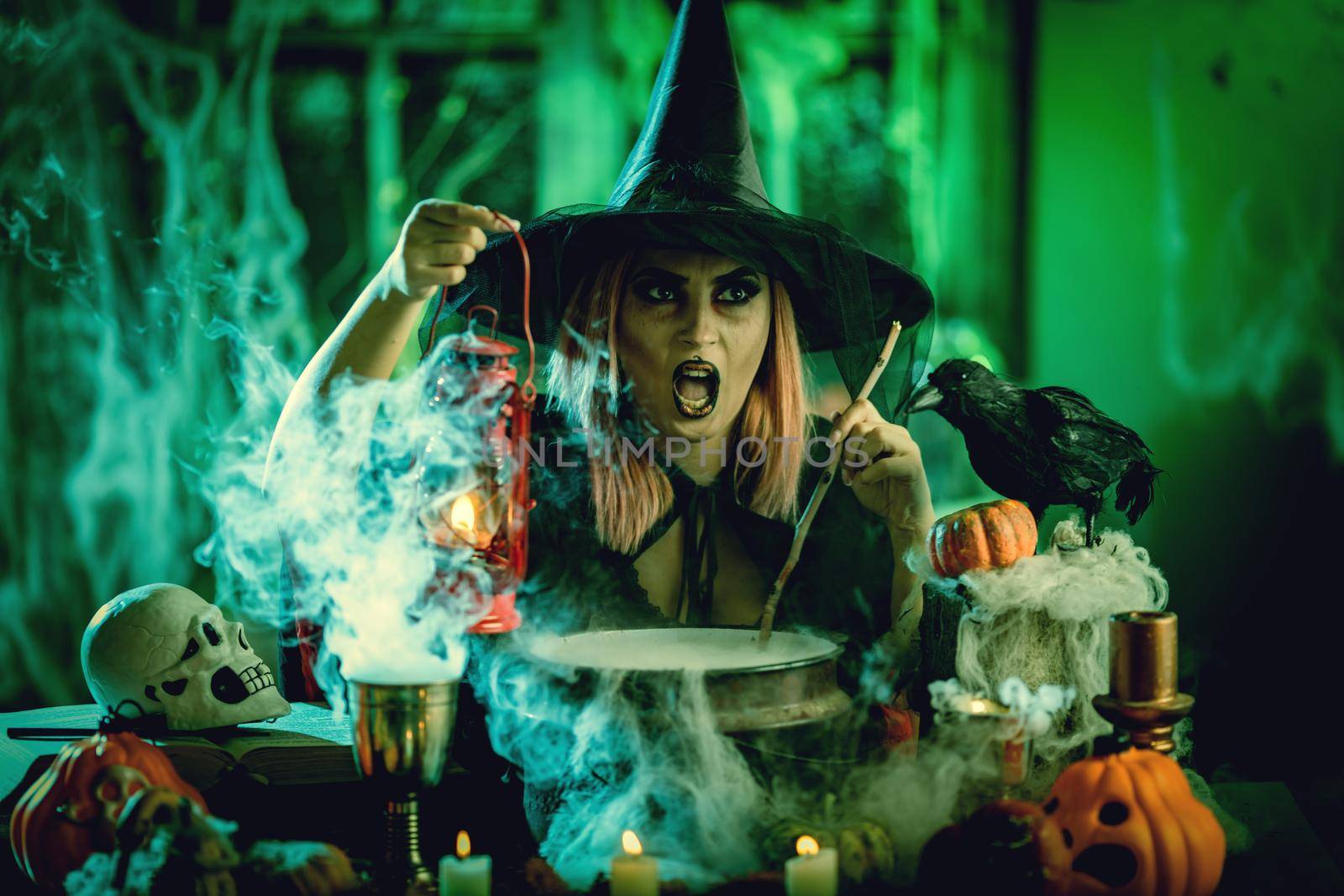 Witch with smiling face in creepy surroundings cooks poison soup in boiling cauldron.