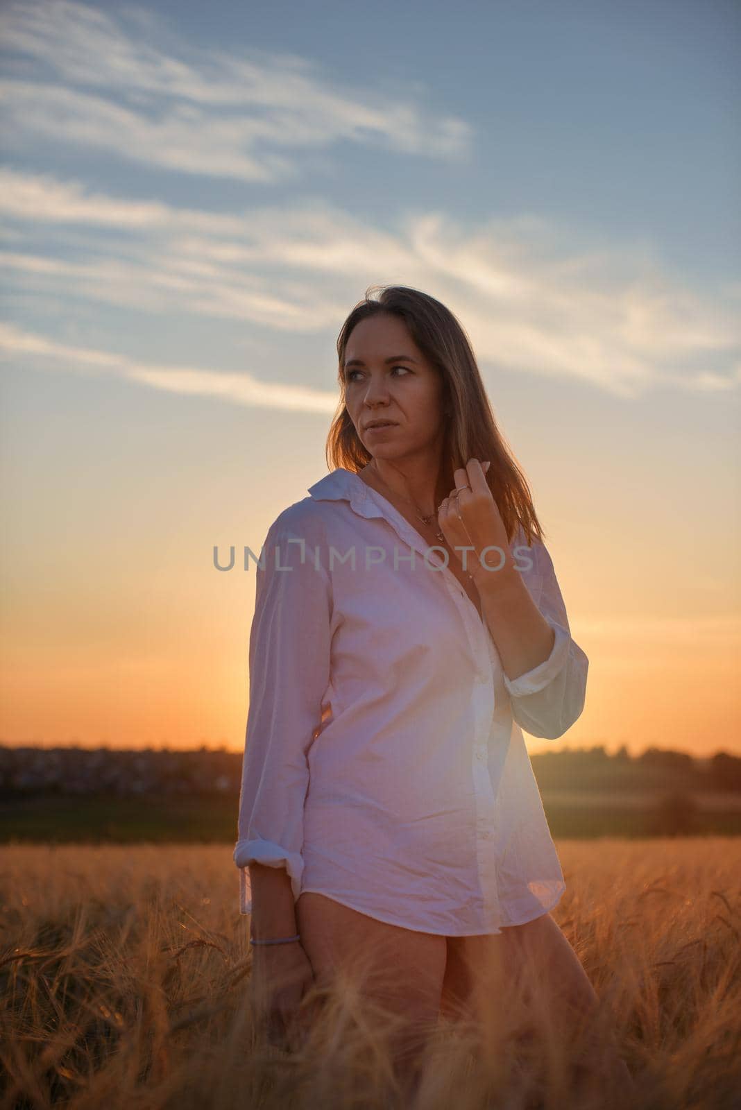 Woman in the yellow field of wheat, beauty summer sunset
