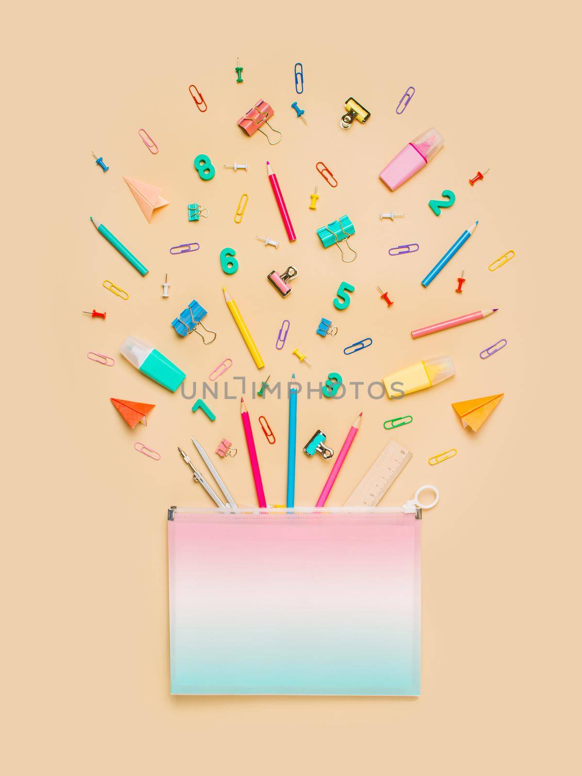 Creative student desk with school supplies and copy space on gradinet document case. Top view or flat lay. Trendy back to school flat lay on neutral pastel beige background. Vertical