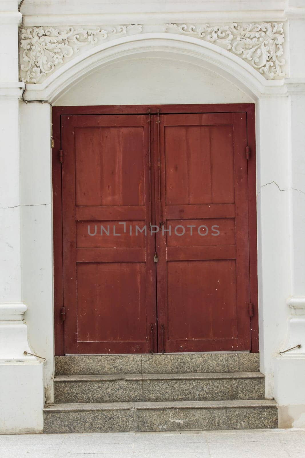 Old brown wood doors on white walls are closed.