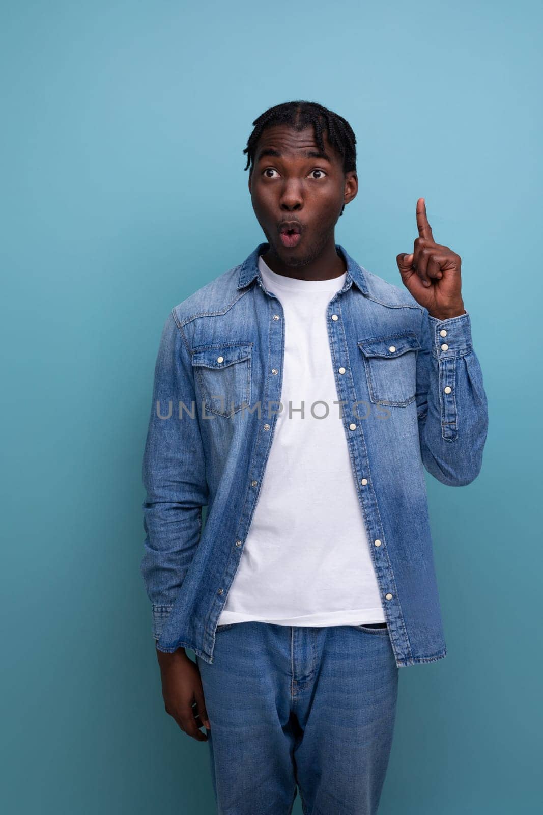 portrait of a surprised young cheerful american man with dreadlocks in a denim jacket.