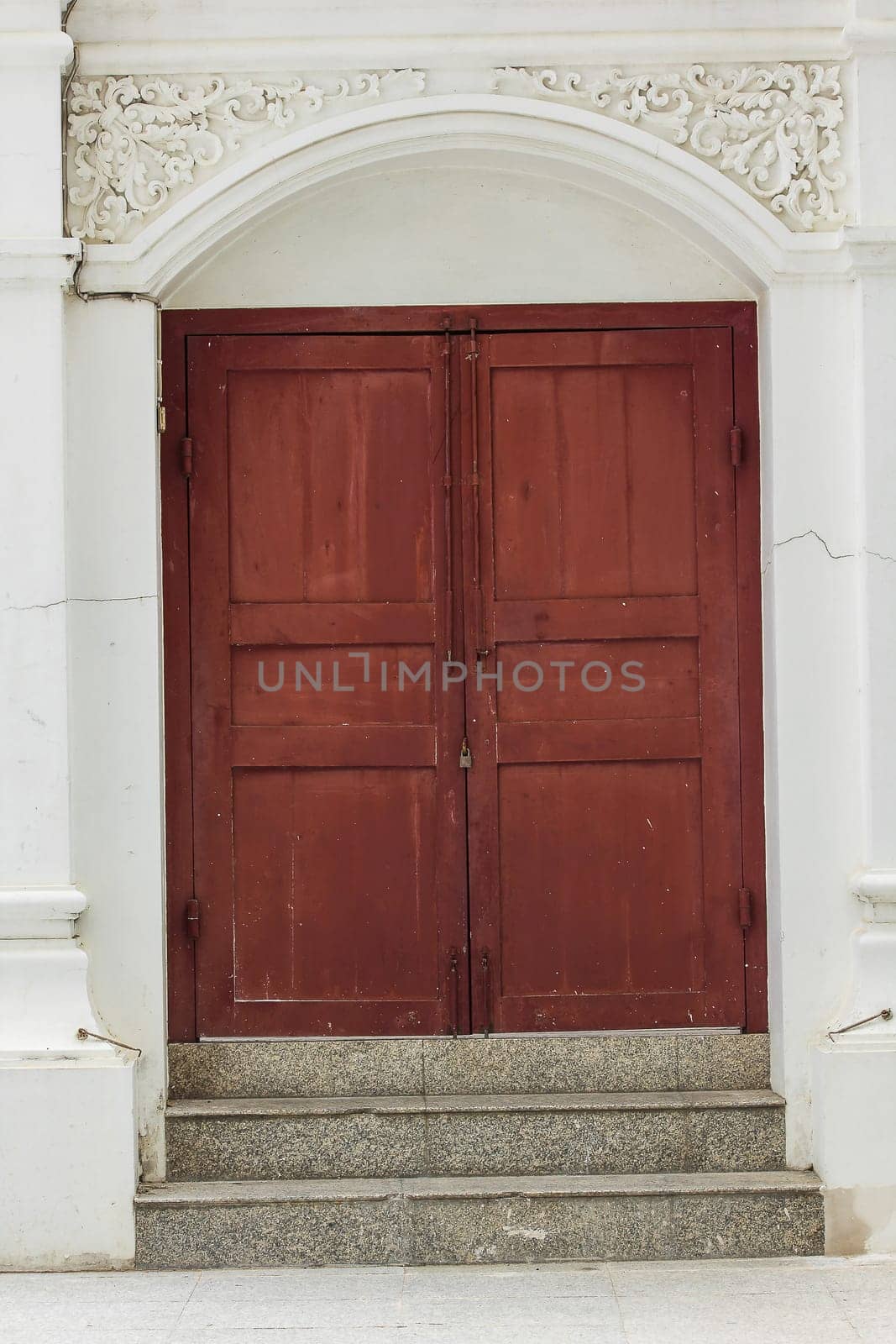 Old brown wood doors on white walls are closed.