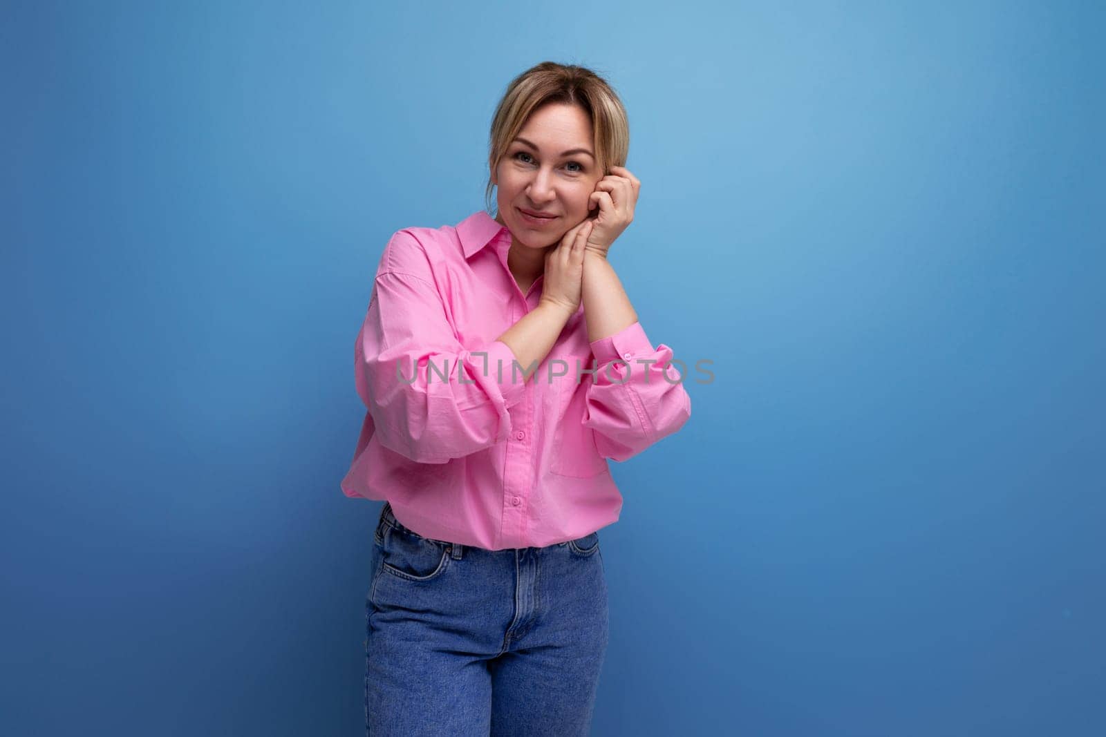 stylish young blond businesswoman in pink shirt and jeans on studio background with copy space.