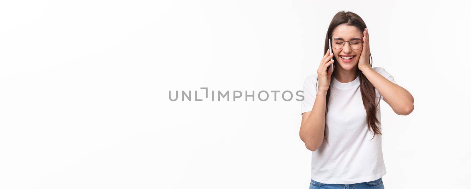 Communication, technology and lifestyle concept. Portrait of excited and happy, overwhelmed young caucasian woman receive excellent news, smiling and laughing, talking on mobile phone.