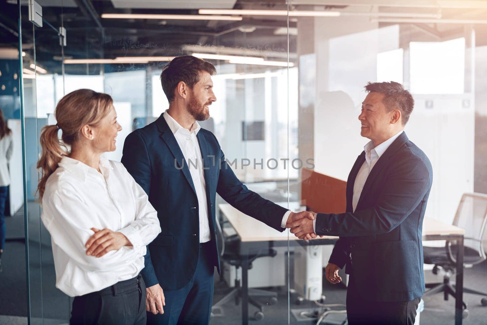 Welcome to our team, mature modern men in formal wear shaking hands in modern office.