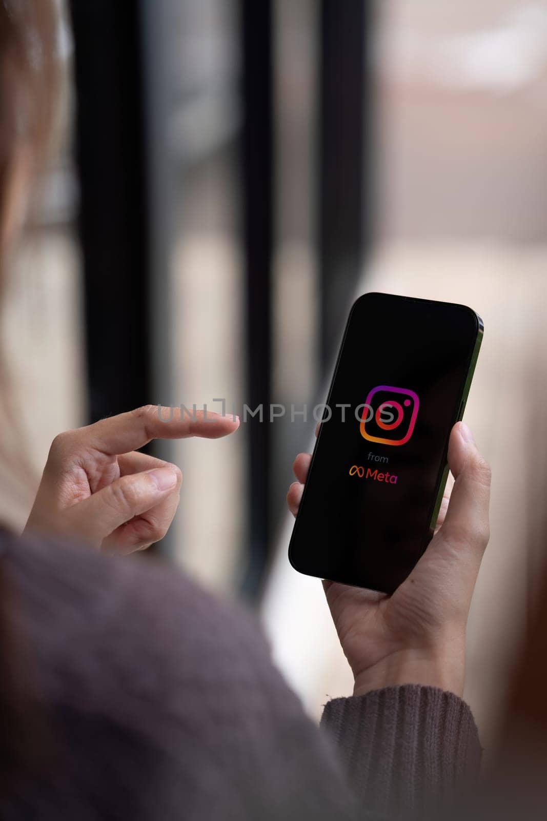 CHIANG MAI, THAILAND - AUG 08, 2023: A woman holds Apple iPhone 14 Pro Max with Instagram application on the screen at cafe. Instagram is a photo-sharing app for smartphones..