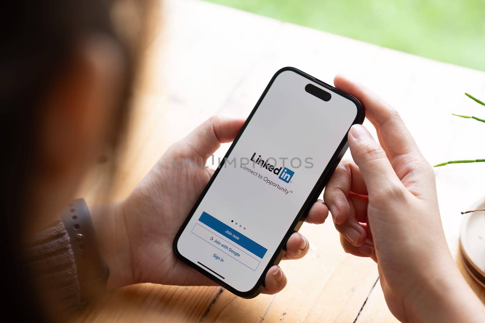 CHIANG MAI, THAILAND - AUG 08, 2023 : A women holds Apple iPhone 14 Pro Max with LinkedIn application on the screen.LinkedIn is a photo-sharing app for smartphones..