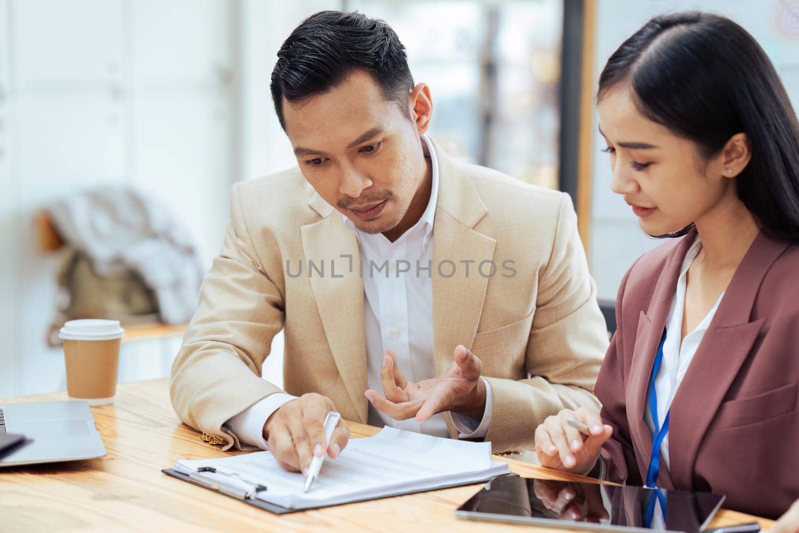 Businessman manager explaining and coaching Asian colleague financial project on paperwork.