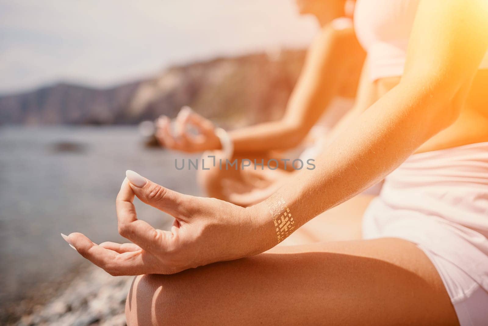 Woman sea yoga. Happy women meditating in yoga pose on the beach, ocean and rock mountains. Motivation and inspirational fit and exercising. Healthy lifestyle outdoors in nature, fitness concept. by panophotograph