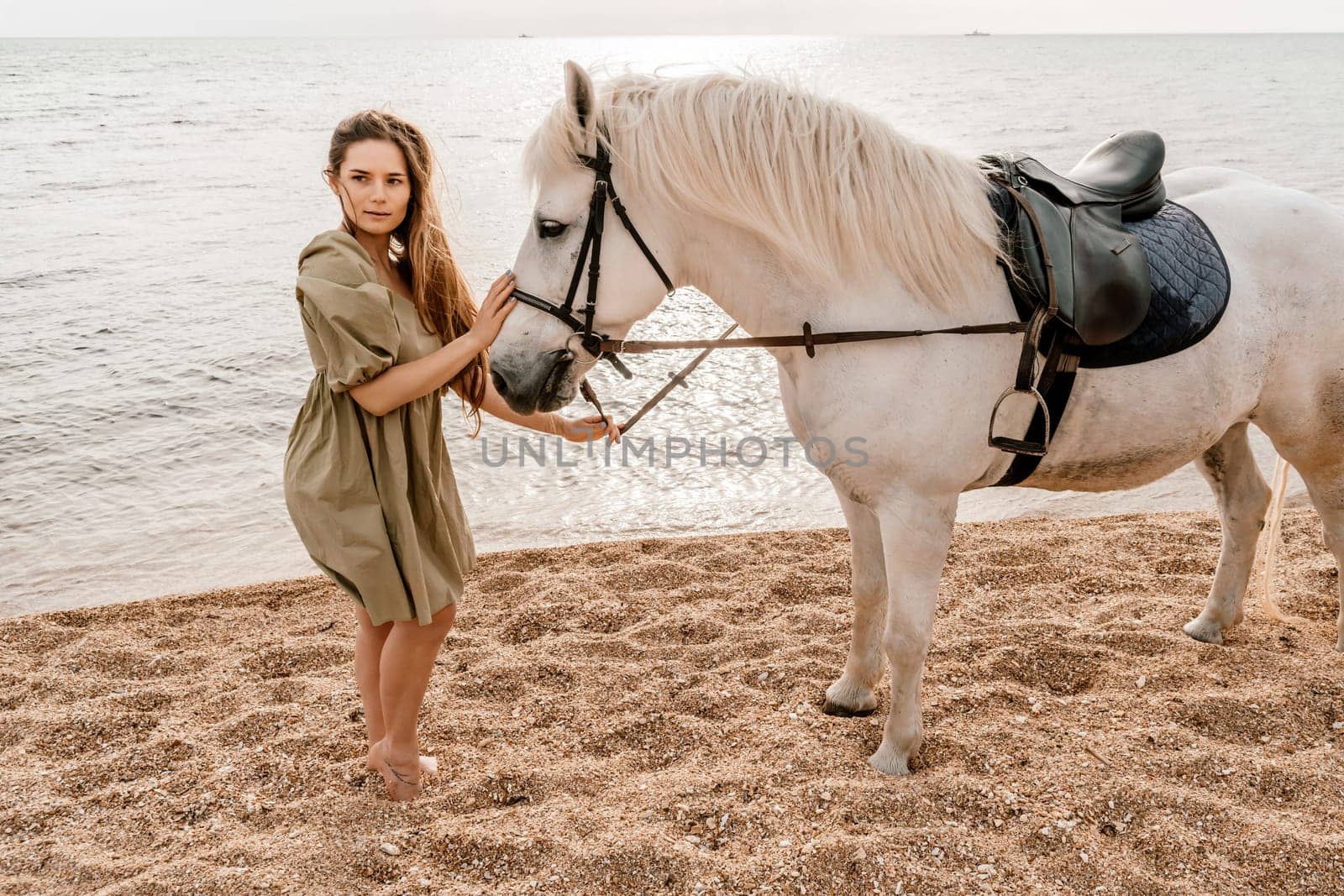 A white horse and a woman in a dress stand on a beach, with the sky and sea creating a picturesque backdrop for the scene. by Matiunina