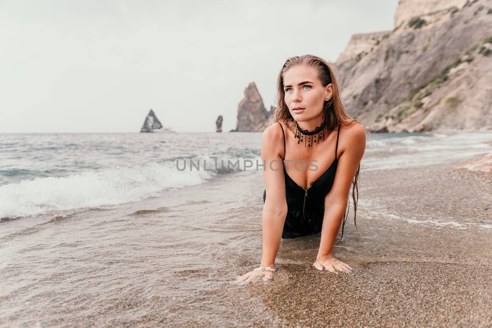 Woman travel sea. Young Happy woman in a long red dress posing on a beach near the sea on background of volcanic rocks, like in Iceland, sharing travel adventure journey