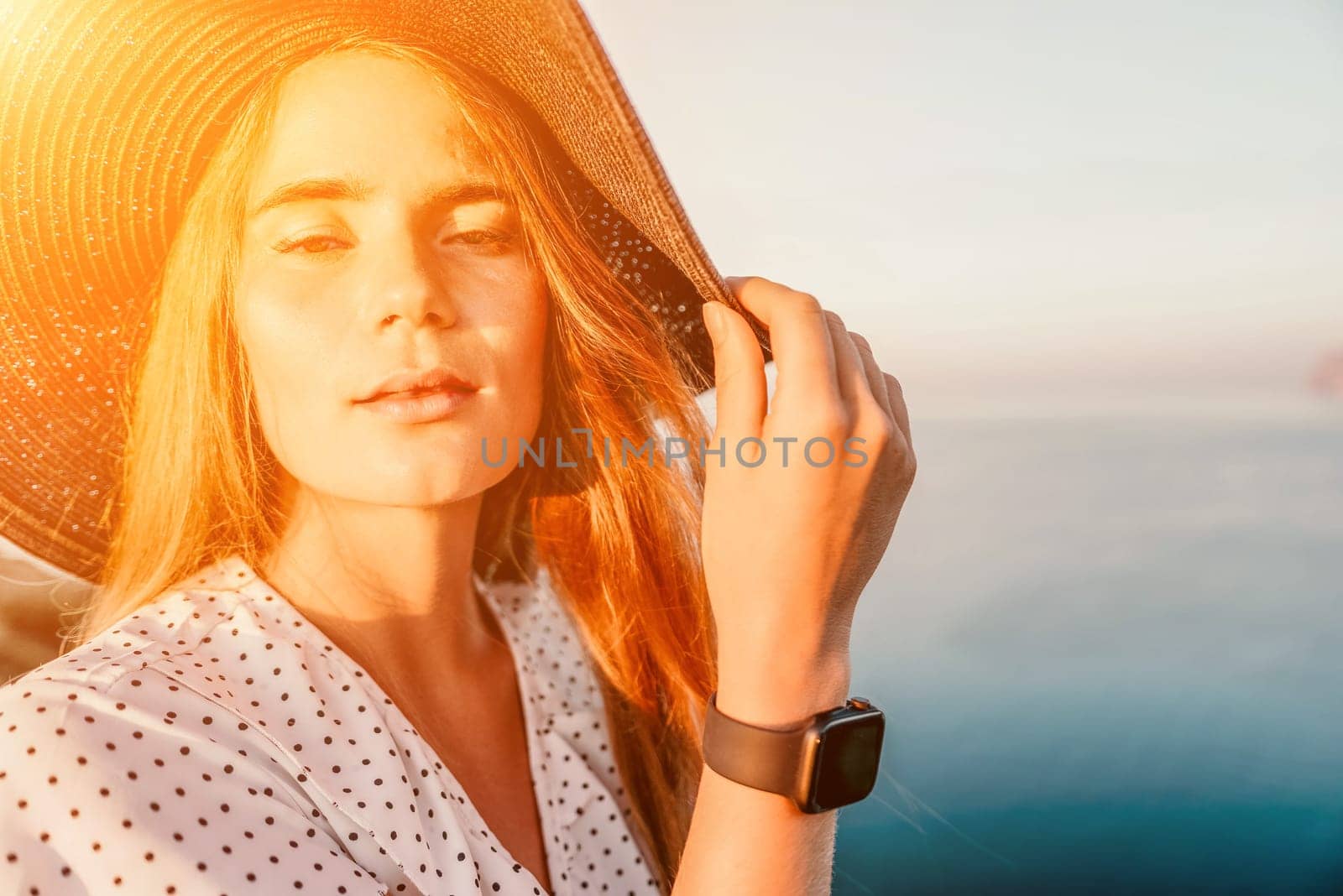 Portrait of happy young woman wearing summer black hat with large brim at beach on sunset. Closeup face of attractive girl with black straw hat. Happy young woman smiling and looking at camera at sea. by panophotograph