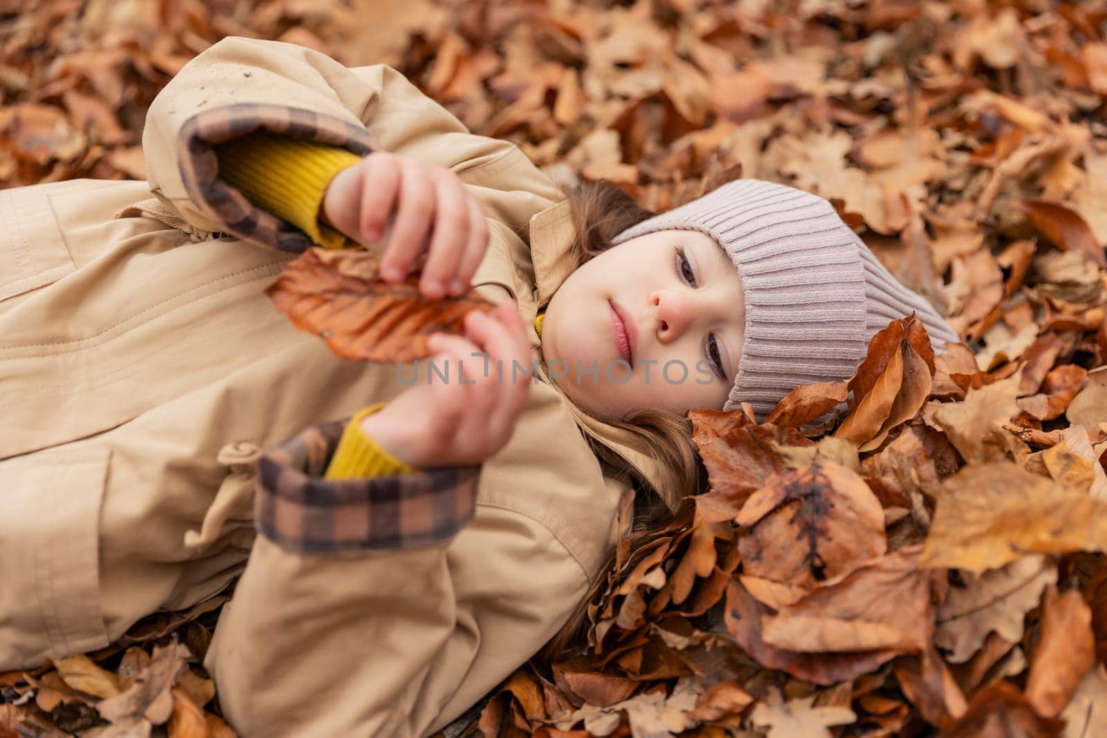 portrait of a little girl lying in fallen autumn leaves