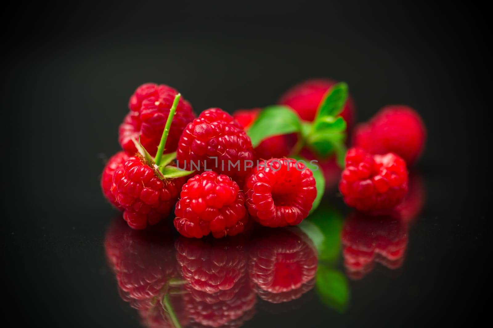 Ripe red raspberries closeup, isolated on black background.