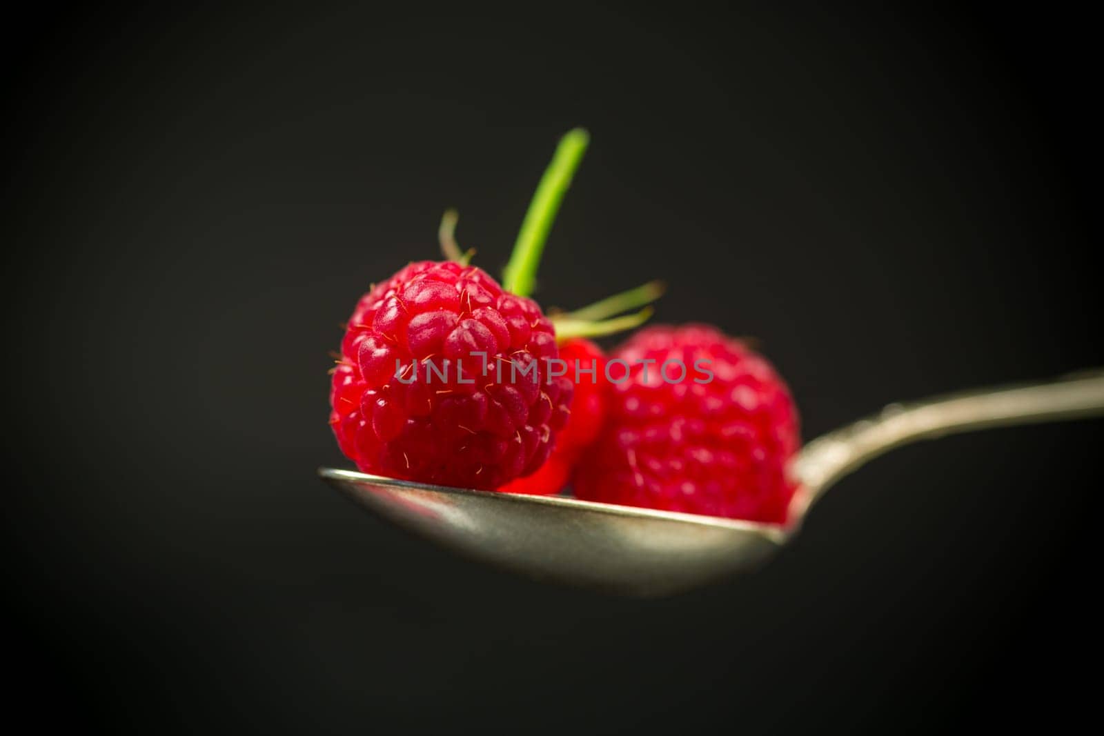 Ripe red raspberries closeup, isolated on black background.