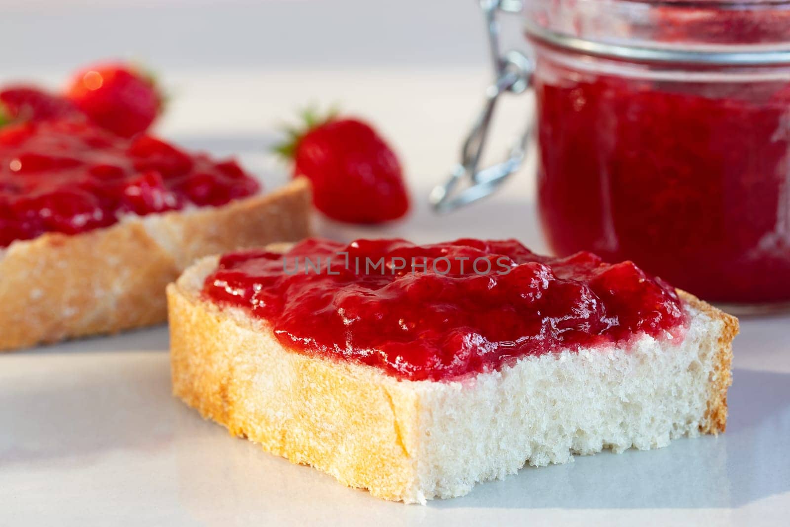 Wheat bread toasts with spread strawberry jam on the table by galsand