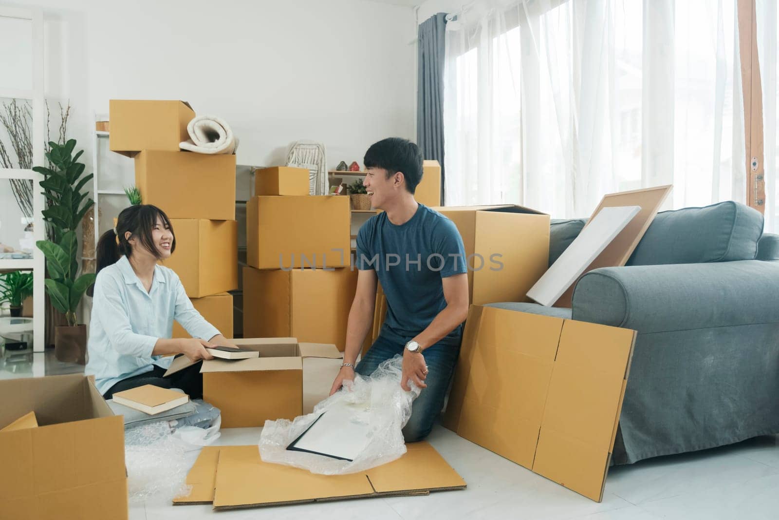 Young married couple moving into new home. They're unpacking or packing card boxes with their accessories.