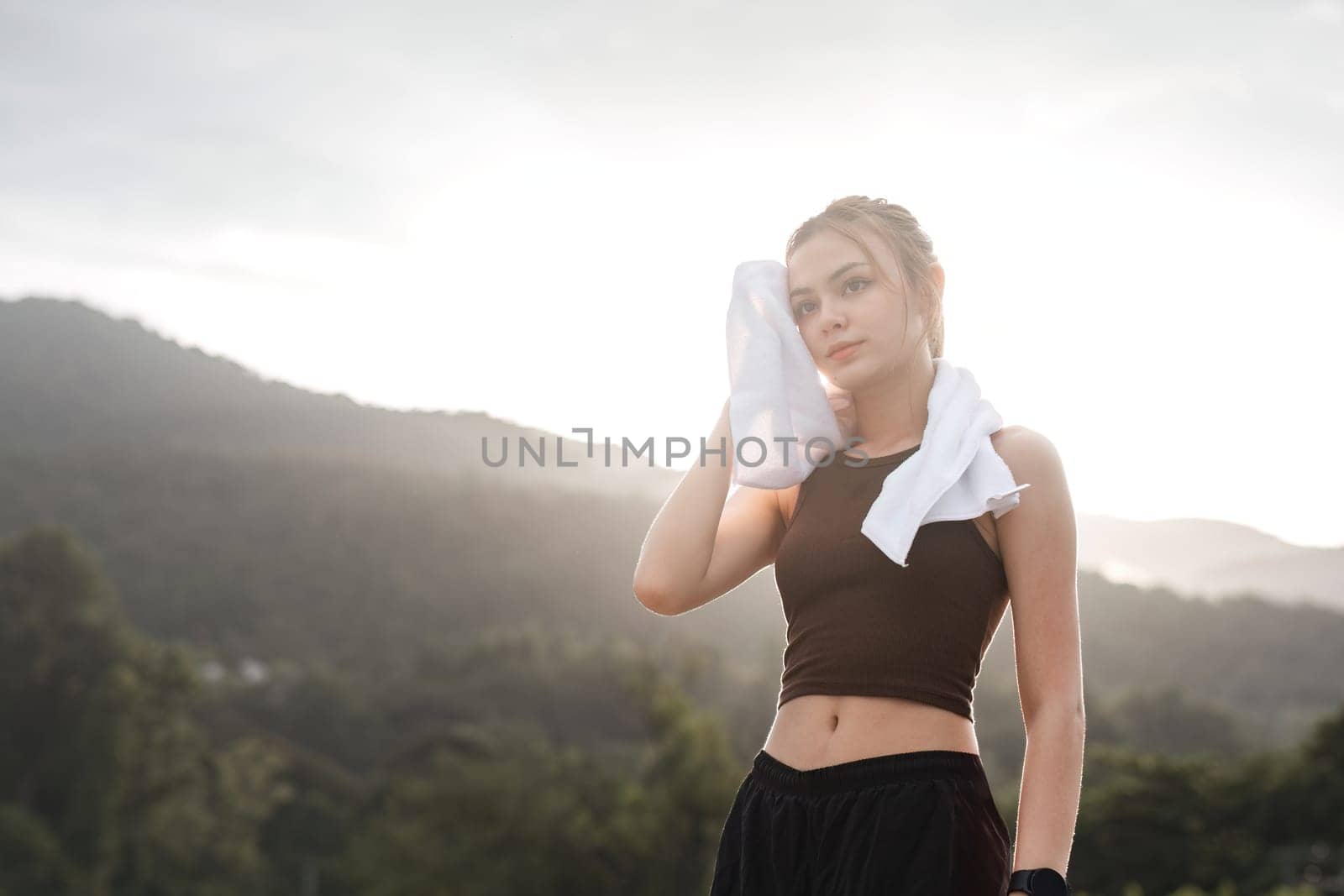 Portrait Young beautiful Asian woman wiping sweat after evening jogging in the park..