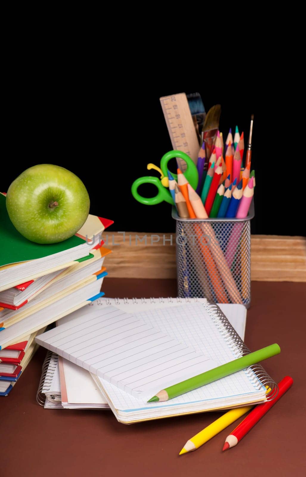 board, books, pencils, opened empty notebook against a dark background