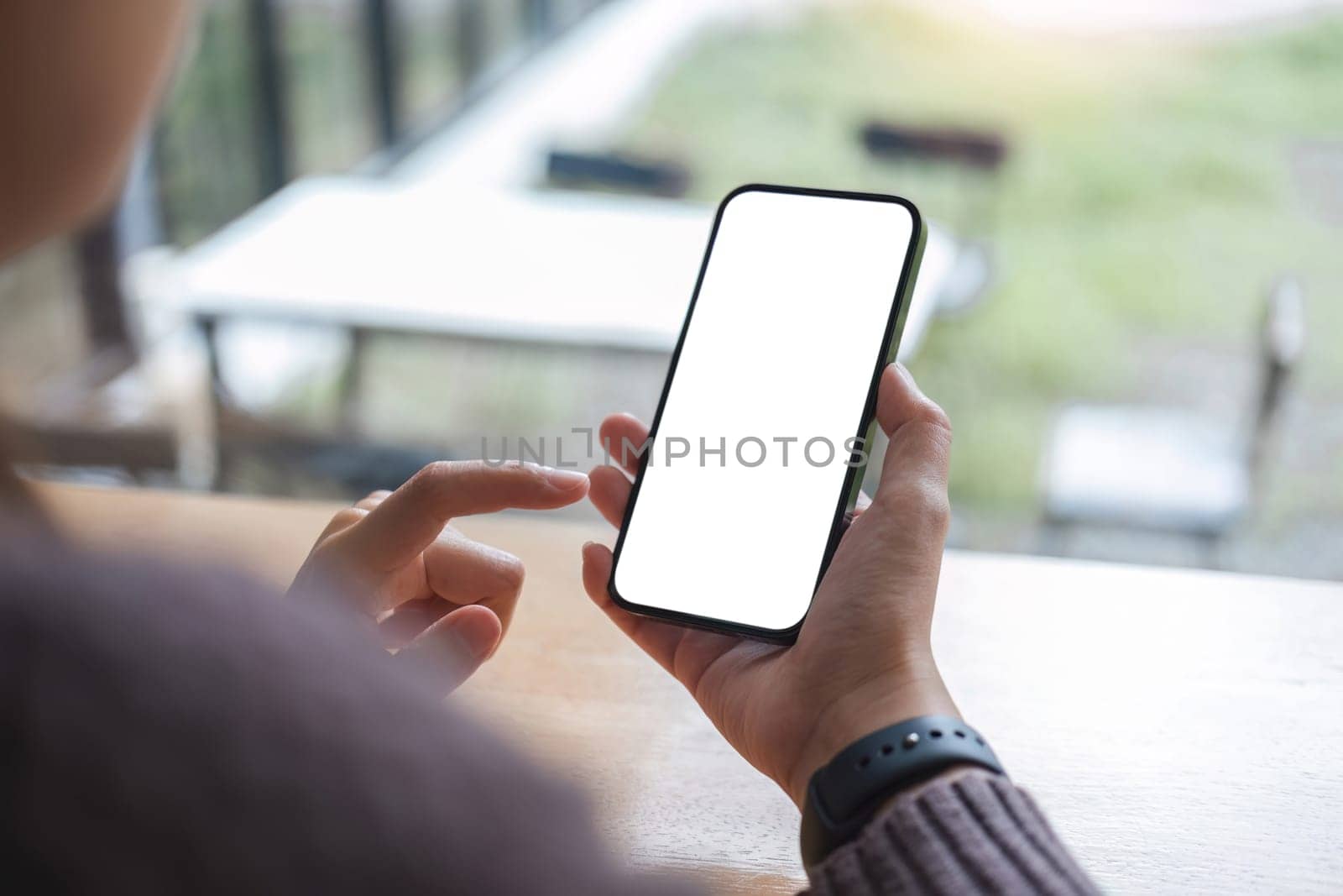 Mockup image of closeup woman hand holding mobile phone with blank white smartphone screen at the outdoor..