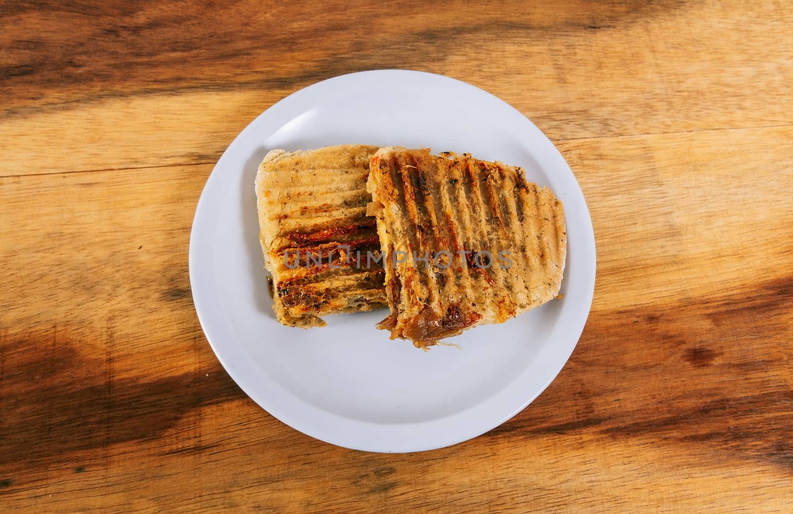 Top view of two meat and chicken panini on wooden table by isaiphoto