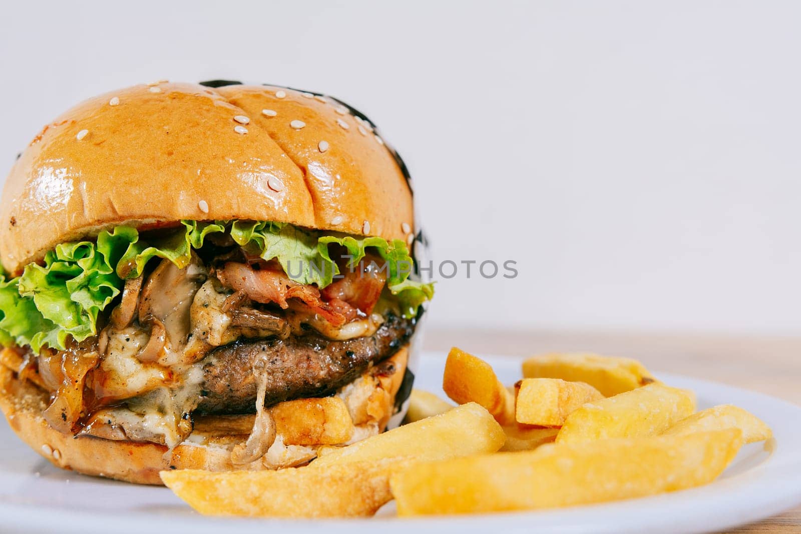 Big cheeseburger with fries served with copy space. Homemade burger with french fries on a plate on wooden table by isaiphoto