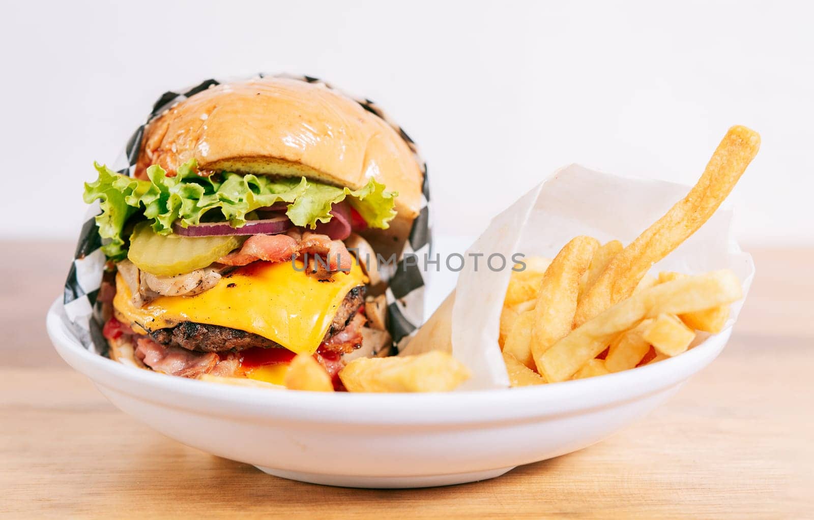 Cheeseburger with fries on wooden table. Close up of a delicious hamburger with french fries on wooden table with copy space