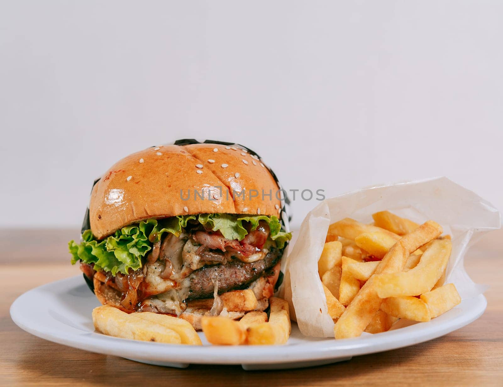 Close up of a delicious hamburger with french fries on wooden table with copy space. Cheeseburger with fries on wooden table by isaiphoto