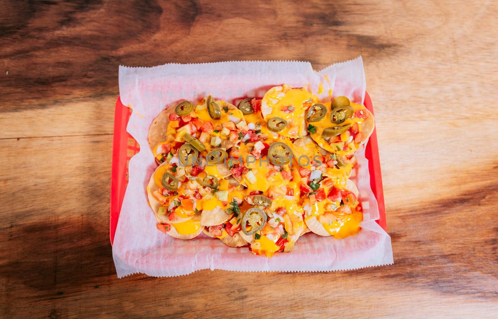 Top view of homemade nachos with jalapeno and melted cheese on wooden table. Mexican nachos with melted cheese and jalapeno