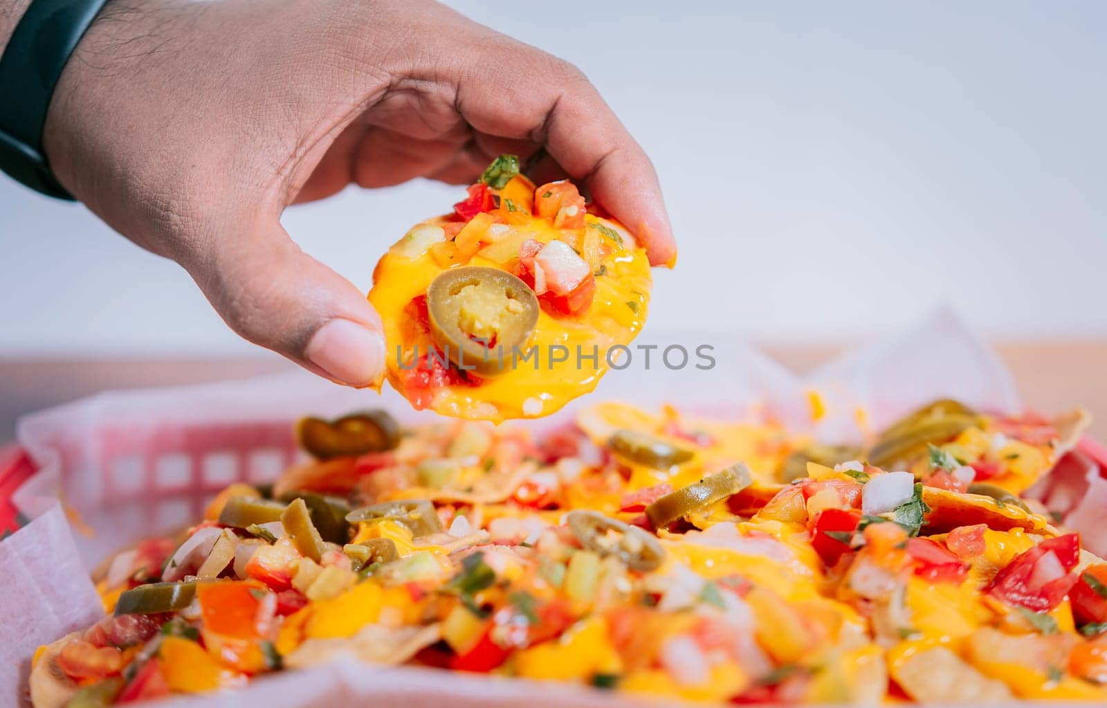 Close up of hand of taking nachos on isolated background. Hand taking and showing a nacho isolated by isaiphoto