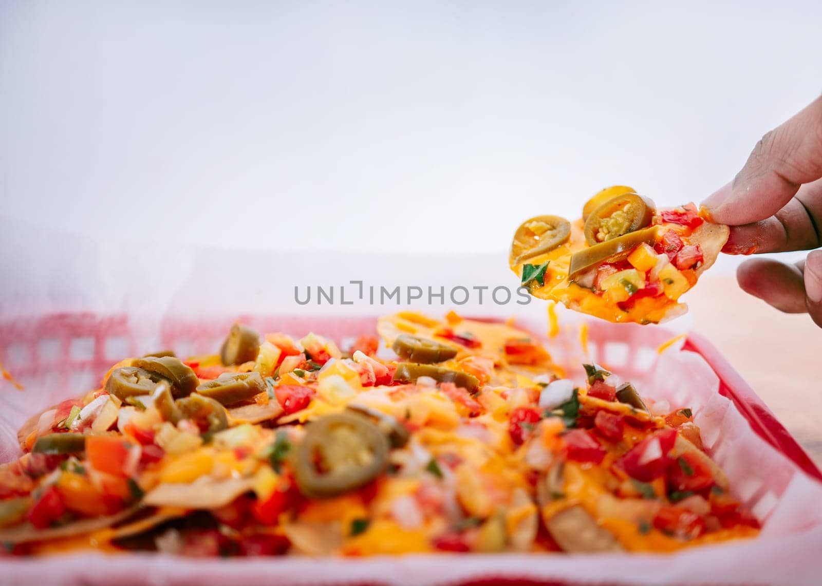 Hand of people taking nachos on isolated background. Hand taking nachos from a tray by isaiphoto